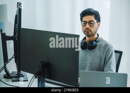 Der Prompt-Ingenieur des asiatischen Mannes entwickelt eine Codierungs-App mit Softwaredaten, die vor dem Computermonitor im Büro sitzen Stockfoto