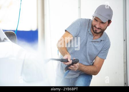 Mann Reinigung Auto mit hohem Druck Wasser Stockfoto