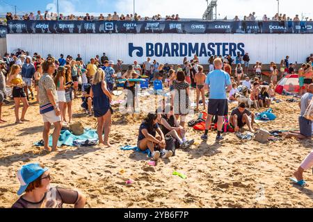 Urlauber Zuschauer, die beim Boardmasters Surfing Festival begeistert surfen, genießen die Sommersonne am berühmten Fistral Beach Stockfoto