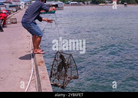 Phu Quoc, Vietnam 17. Mai 2018 - ein einheimischer Mann holt an sonnigem Tag am Steg im Fischerdorf Ham Ninh eine Metallfalle aus dem Meer. Stockfoto