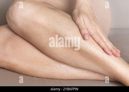 Die Frau zeigt ihre behaarten Beine, sie braucht Epilierung, Enthaarung. Nahaufnahme Stockfoto