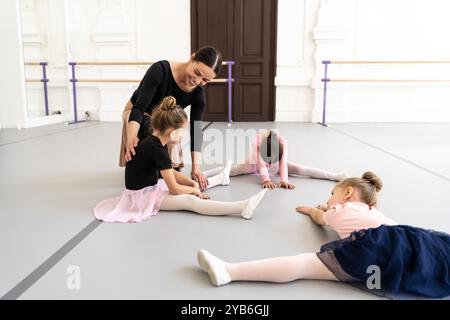 Die Trainerin der Ballettschule hilft jungen Ballerinas bei verschiedenen choreografischen Übungen Stockfoto