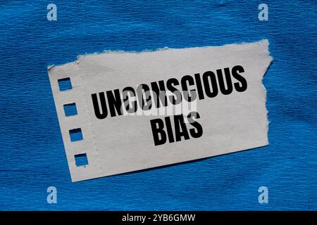 Unbewusste Vorurteilsbotschaft auf zerrissenem Papierstück mit blauem Hintergrund. Konzeptuelles unbewusstes Vorurteil-Symbol. Kopierbereich. Stockfoto