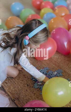 Geburtstag meiner 5-jährigen Tochter. Sie hört Musik über Kopfhörer und sammelt ein Puzzle. Hochwertige Fotos Stockfoto