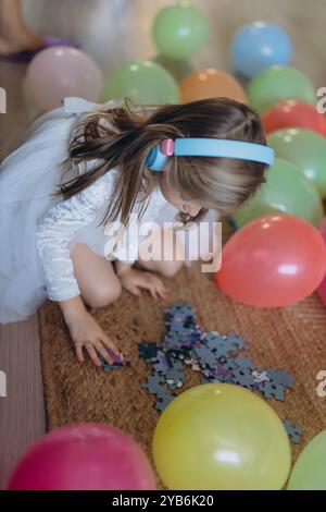 Geburtstag meiner 5-jährigen Tochter. Sie hört Musik über Kopfhörer und sammelt ein Puzzle. Hochwertige Fotos Stockfoto