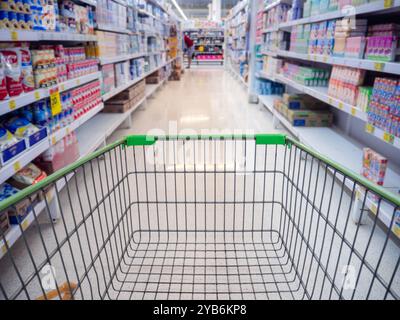 Einkaufswagen im Kaufhaus abstrakt verschwimmt von bunten Regalen, Einkaufswagen im Supermarkt. Leere rote Warenkorbansicht mit warmem Licht. Stockfoto