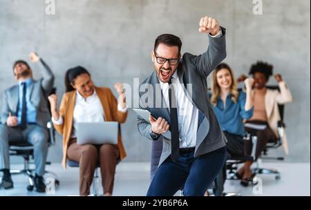 Das Team ist begeistert von verschiedenen Geschäftsleuten und feiert gemeinsam im Büro den Unternehmenssieg Stockfoto