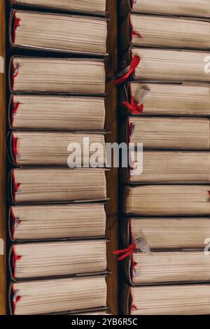 Blick von oben auf Reihen alter Bücher mit abgenutzten Seiten und roten Lesezeichen, ordentlich auf Holzregalen angeordnet. Hochwertige Fotos Stockfoto