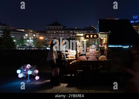 xi'an, China - 23. September 2024: Ein Mann verkauft nachts in Shaanxi im Zentrum von CH Souvenirs an einem Stand an der Stadtmauer von Xi'an Stockfoto