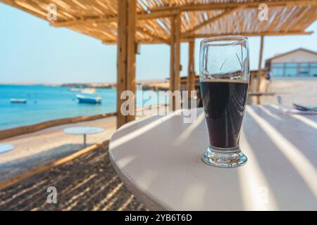 Ein Glas Bier steht draußen am Meer auf einem Tisch Stockfoto