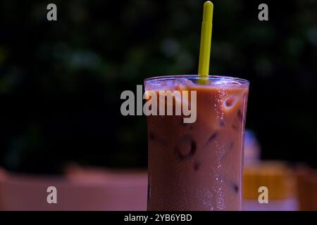 Kaffee mit Orangensaft Hummeln in einem hohen Glas mit Eis und Minze auf einem Holzbrett auf einem hellen Hintergrund mit Kaffeebohnen, Früchten und Morgenschatten. Trendiges asiatisches Erfrischungsgetränk im Sommer. Stockfoto