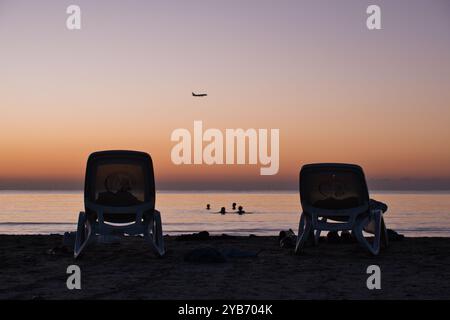 Schwimmer warten auf Sonnenaufgang am Strand von Finikoudes in Zypern Stockfoto