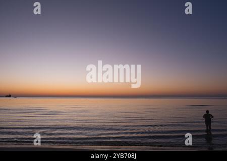 Frau im Meer bei Sonnenaufgang am Strand von Finikoudes auf Zypern Stockfoto