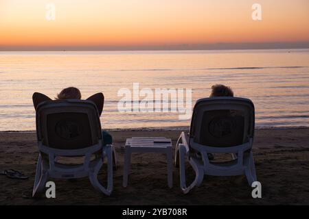 Pärchen, die auf Sonnenaufgang am Strand von Finikoudes in Zypern warten Stockfoto