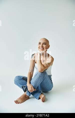 Eine junge kahlköpfige Frau mit Alopezie lächelt hell und feiert ihre Schönheit in einer ruhigen Umgebung. Stockfoto