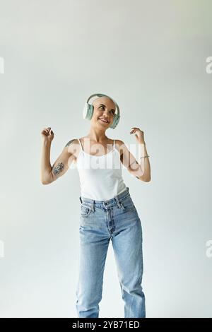 Eine junge Frau mit Alopezie genießt gerne Musik und tanzt fröhlich in einem ruhigen Raum. Stockfoto