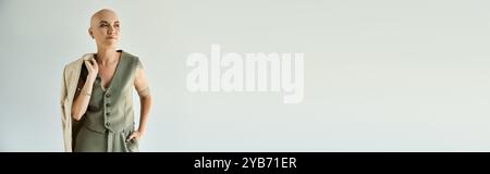 Eine junge Frau mit Alopezie steht selbstbewusst, elegant gekleidet in einer minimalistischen Umgebung. Stockfoto