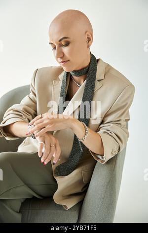 Eine junge kahlköpfige Frau mit Alopezie, elegant gekleidet, spiegelt Selbstvertrauen in einem ruhigen Moment wider. Stockfoto