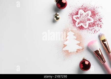 Weihnachtsdekorationen aus Puder und Rouge, Kugeln und Make-up-Pinsel auf weißem Hintergrund, flach gelegt. Leerzeichen für Text Stockfoto