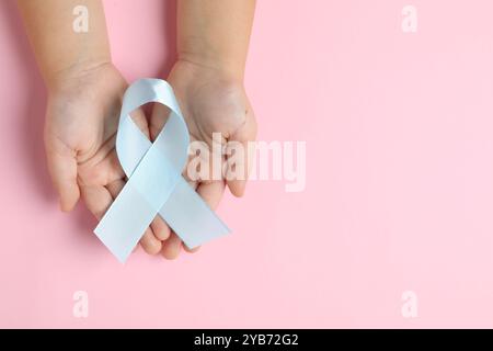 Kind mit hellblauem Band auf rosafarbenem Hintergrund, Draufsicht und Platz für Text. Krebsbewusstsein im Kindesalter Stockfoto