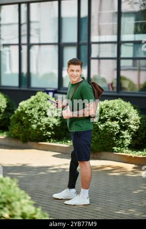 Ein gutaussehender junger Mann steht draußen und zeigt selbstbewusst seine Beinprothese, während er die Natur genießt. Stockfoto