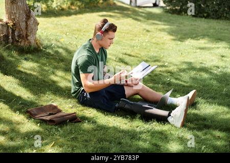 Ein junger Mann entspannt sich auf dem Gras, liest ein Buch, während er eine Beinprothese trägt und die Sommerzeit genießt. Stockfoto