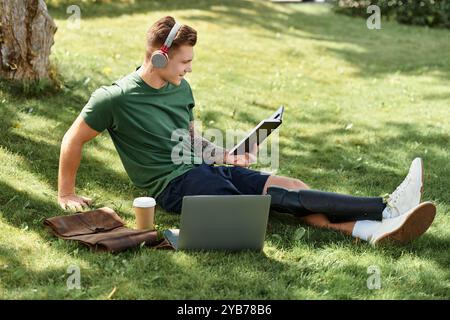 Ein junger Mann mit einer Beinprothese lächelt, während er ein Buch über üppiges grünes Gras im Park liest. Stockfoto