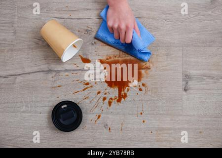 Pappbecher Kaffee fiel auf Laminat, Kaffee verschüttete auf den Boden. Stockfoto