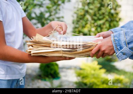 Das Mädchen hält einen Stapel Zeitungen in der Hand. Ökologie. Das Kind übergibt Papier für Altpapier. Stockfoto