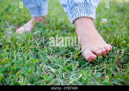 Das Kind läuft barfuß auf dem Gras. Stockfoto