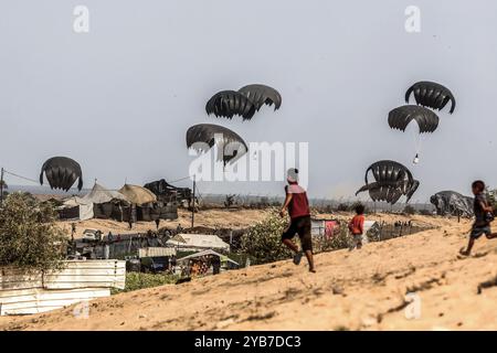 Al Mawasi, Palästinensische Gebiete. Oktober 2024. Vertriebene Palästinenser streben nach Nahrungsmittelhilfe, da die humanitäre Hilfe der Emirate im Gebiet Al-Mawasi westlich von Khan Yunis im südlichen Gazastreifen aus Flugzeugen mit Fallschirmen landet. Abed Rahim Khatib/dpa/Alamy Live News Stockfoto