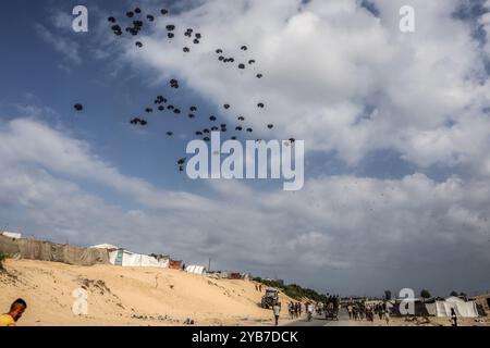 Al Mawasi, Palästinensische Gebiete. Oktober 2024. Vertriebene Palästinenser streben nach Nahrungsmittelhilfe, da die humanitäre Hilfe der Emirate im Gebiet Al-Mawasi westlich von Khan Yunis im südlichen Gazastreifen aus Flugzeugen mit Fallschirmen landet. Abed Rahim Khatib/dpa/Alamy Live News Stockfoto