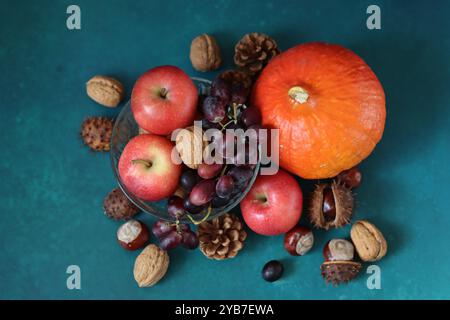 Die Zutaten für das Komfortessen auf dem Tisch. Buntes Stillleben mit Kürbis, Äpfeln, Nüssen und Blumen. Konzept der Herbsternte. Stockfoto