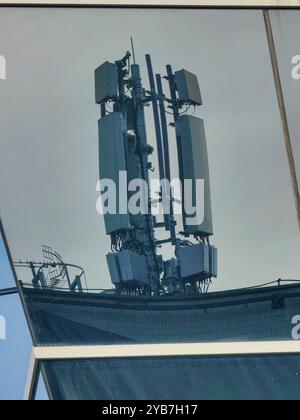 Reflexion in Glas: 5G-Zellturm im Fensterrahmen Stockfoto