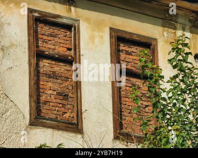 Verlassenes Haus: Zwei alte Holzfenster Rahmen mit Ziegeln verbarrikadiert. Stockfoto