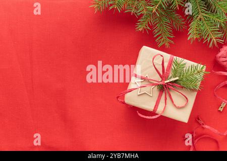 Weihnachten und Zero Waste, umweltfreundliches natürliches Verpackungsgeschenk in Bastelpapier auf rotem textilem Hintergrund, Öko-Weihnachtskonzept, Öko-Dekorationsverbot Stockfoto