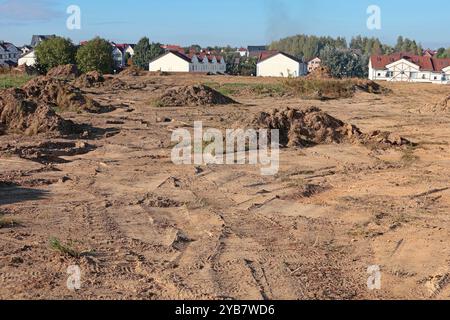 Bodenbelag für den Bau neuer Wohngegenstände. Grundstückshaufen auf der Baustelle vor dem Hintergrund von gebauten Häusern. Gebäude und Stockfoto