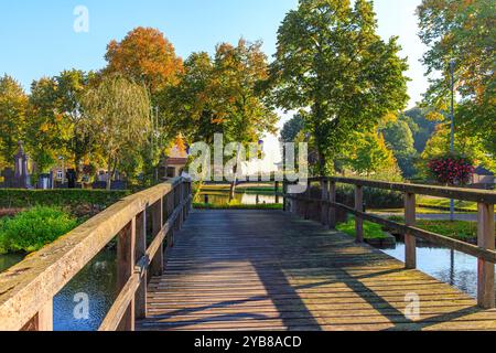 Holzbrücke über den Burggraben führt zum öffentlichen Park mit Teich im Hintergrund, herbstliche Bäume im Hintergrund, sonniger Tag in Wijnandsrade, Süd-Limburg, Stockfoto