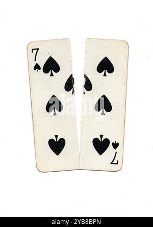 Eine alte Spielkarte, die von oben nach unten in zwei Hälften auf weißem Hintergrund zerrissen wurde. Stockfoto