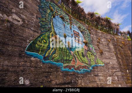 Farbenfrohes Straßenkunstgemälde, das Natur und lokale Kultur auf einer geschwungenen Betonwand in Seixal darstellt Stockfoto