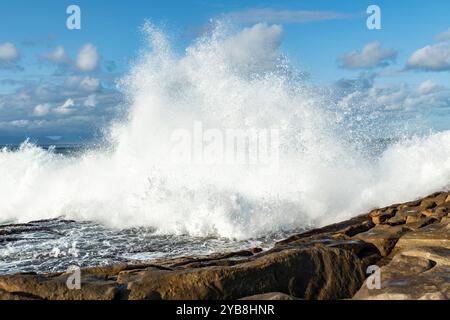 Eine große Welle, die gegen die Felsen der felsigen Küste kracht Stockfoto