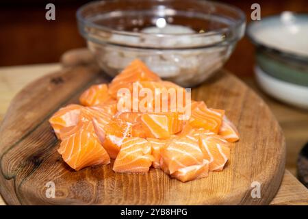 Ein frischer Haufen geschnittenen Lachses auf einem hölzernen Häckselblock in einer Küche, fertig zum Kochen Stockfoto