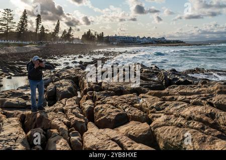 Ein Fotograf, Tourist, der ein Foto entlang der felsigen Küste von The Point in Mossel Bay in Südafrika macht Stockfoto