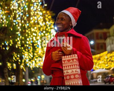 Junge Frau mit Weihnachtsmütze, die nachts auf der Straße läuft Stockfoto