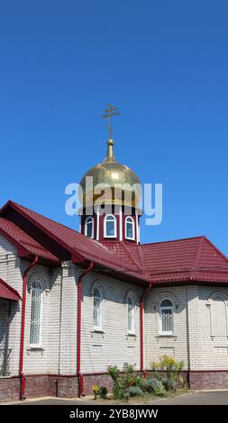 Vertikales Bild einer orthodoxen Kapelle oder kleinen Kirche mit einer goldenen Kuppel und rotem Dach an sonnigem Tag, religiöse christliche Architektur kleine Formen Stockfoto