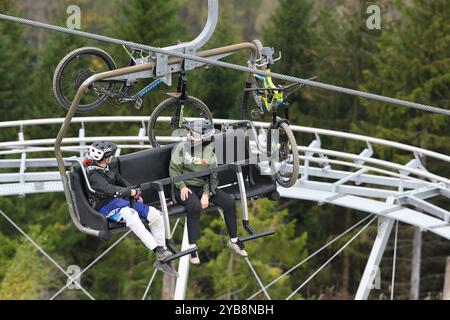 Hahnenklee, Deutschland. Oktober 2024. Mountainbiker sitzen im Sessellift auf dem Bocksberg vor dem Gerüst der neuen Sommerrodelbahn im Harz. Die Sommersaison auf dem 727 Meter hohen Bocksberg im Landkreis Hahnenklee Goslar dauert bis zum 27.10.2024. Quelle: Swen Pförtner/dpa/Alamy Live News Stockfoto