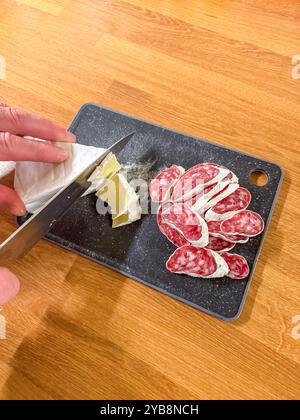 Schneiden von Wurst auf einem Schneidebrett für die Zubereitung von Charcuterie-Platten. Hochwertige Fotos Stockfoto