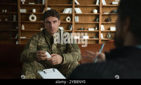 Ernsthaft ruhiger Kaukasier männlicher Militär Soldat Offizier Tarnuniform Kerl hält Flaschenbecher Pillen Antidepressiva Schmerzmittel reif Stockfoto