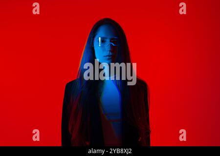 Cyberpunk-Porträt in Futuristic Modern Young Woman with Smart Briasses Standing a Red Glowing Background Stockfoto