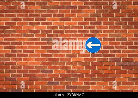 Einbahnschild an einer roten Ziegelmauer Stockfoto